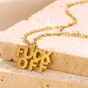 Poliertes Gold FUCK OFF Buchstaben-Halskette auf einem beigen Steinsockel präsentiert