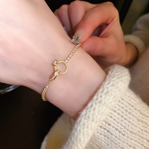 Close-up of gold-plated bamboo link bracelet with zircon stones worn over a white sweater