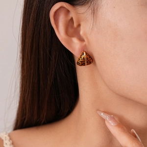 Close-up of a model wearing a geometric triangle leopard print earring with gold plating