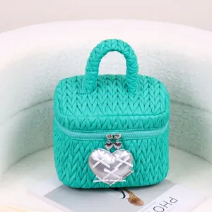 Tiffany blue quilted cosmetic bag with silver heart pendant on white fuzzy background