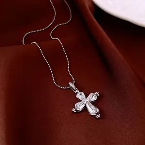 Luxurious silver cross necklace with sparkling zircon stones on a silk background