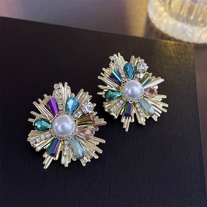 Close-up of vintage flower earrings with pearls and colorful crystals on black background