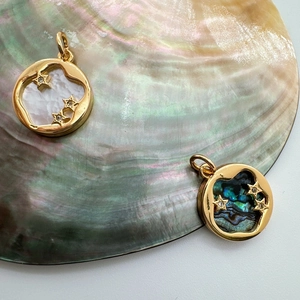 Detail of 18K gold plated charms with white mother of pearl and abalone shell on a large shell