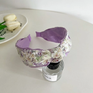 Detail of purple wide headband with white lace flower embroidery and gold accents