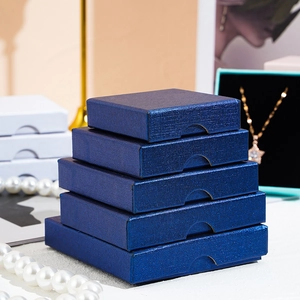 Navy blue textured jewelry gift boxes stacked vertically with luxury pearl accessories