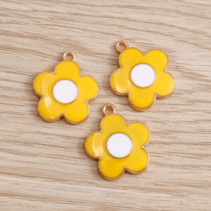 Detailed macro view of yellow enamel daisy flower pendants on a wood surface
