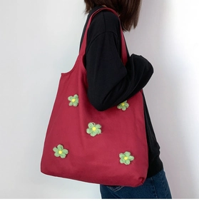 Side view of woman wearing red canvas tote bag with 3D floral plush embroidery details