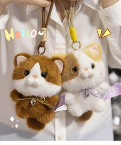 Close-up of plush cat keychains with fluffy fur, metal bells, and woven ropes