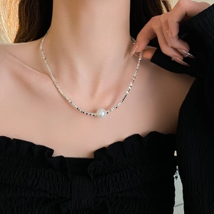 Detail of silver beaded necklace with a central white pearl on a model's neck
