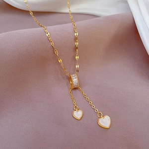 Macro view of gold titanium necklace featuring shell heart charms and sparkling zircons