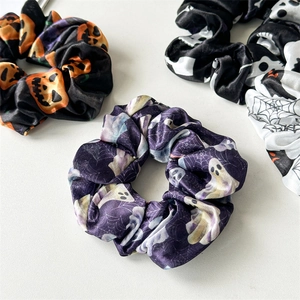Close-up of Halloween scrunchies with pumpkin, skull, and ghost patterns on satin fabric