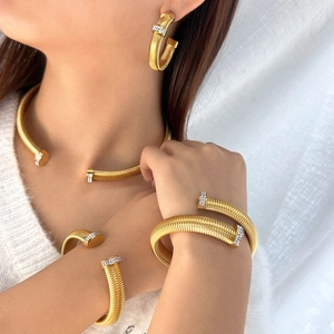 Elegant gold-tone jewelry set featuring spiral snake-inspired necklace, bracelets and earrings