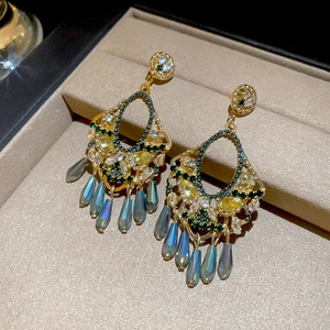 Macro shot of ethnic vintage earrings with gold base, colorful crystals and blue tassels
