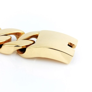 Macro detail of polished gold-finished square clasp on a heavy Cuban link chain