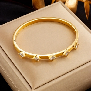 Detailed close-up of a gold bangle set with five square-cut transparent cubic zirconia stones