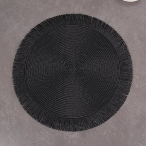 Close-up of black woven placemat with fringe details on a marble textured surface