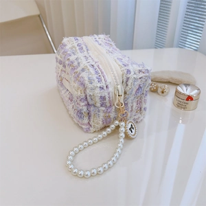 Close-up of purple tweed texture and detachable pearl handle with bow charm detail