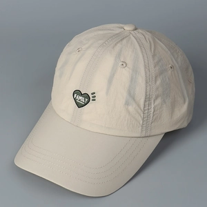 Detail of beige quick-dry baseball cap featuring a heart-shaped Family embroidery patch
