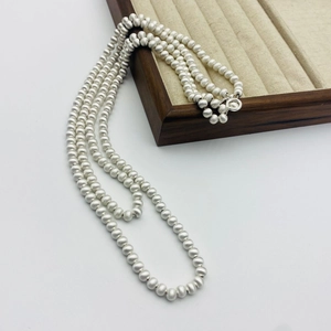 Vue détaillée du collier à trois rangées de perles argentées mates sur plateau