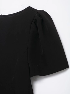 Detail of black puff sleeves and pleated shoulder design on a woven fabric dress