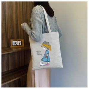 Detailed view of canvas tote bag with girl illustration and shoulder strap on model