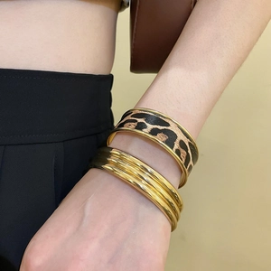 Close-up of leopard print leather and gold layered cuff bracelets set on a woman wrist