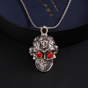 Collier tête de mort punk argent avec yeux en pierres rouges sur boîte à bijoux