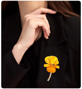 Detail of vintage enamel pansy brooch in yellow and orange on a black suit jacket