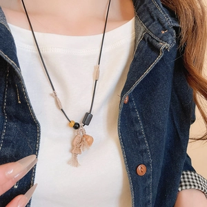 Close-up of a handmade wooden fish pendant necklace with ceramic beads on a model