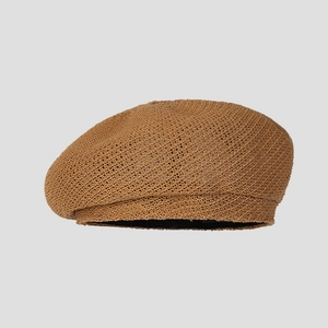 Detailed close-up of a caramel brown knitted beret showing the fine crochet texture