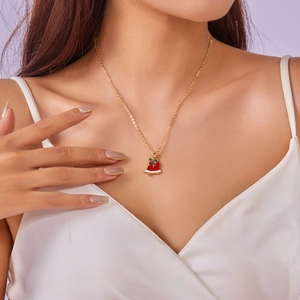 Close-up of a model wearing a gold necklace with a red Christmas stocking pendant