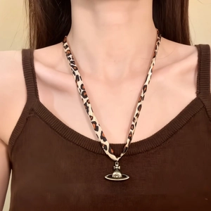 Chic leopard print fabric necklace with gold planet Saturn pendant on a model