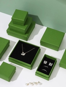 Macro view of green textured jewelry box with crystal swan necklace and rings