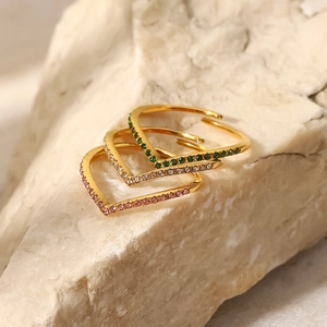 Three stackable gold V-shaped stainless steel rings with green, white, and pink zircons