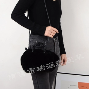 Close-up of black faux fur handbag featuring a woven handle and slender shoulder strap