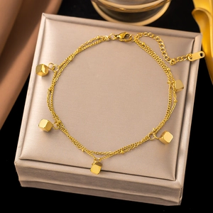 Close-up of double-layer gold titanium anklet with polished cube charms on jewelry box