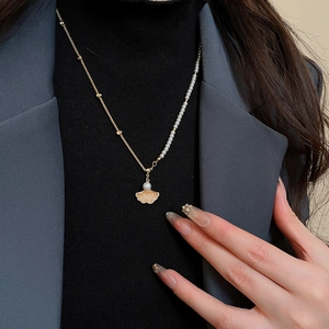 Detailed view of maple leaf pendant with pearls and zircons on a gold-plated necklace
