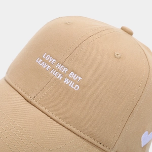 Close-up of white embroidered inspirational text on a khaki cotton baseball cap detail