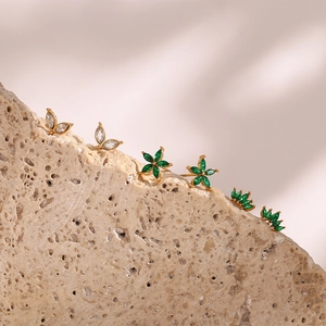 Macro detail of gold plated floral stud earrings with green and white zircon crystals