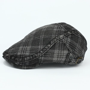 Close-up of vintage grey plaid newsboy cap featuring washed denim texture and metal buckle