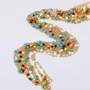 Detail of bohemian gold stainless steel chains with colorful enamel beads in multi-layers