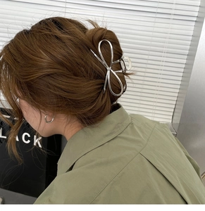 Detail of silver metallic bow hair claw clip styled on a low bun hair arrangement