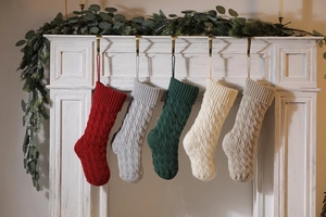 Detail of five knitted Christmas stockings in various colors with cable knit pattern