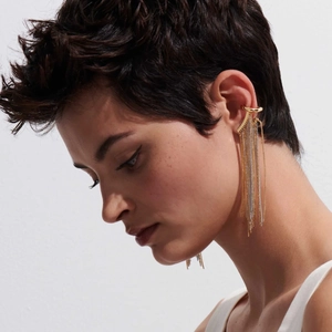 Dettaglio di orecchini ear cuff a nappa bicolore oro e argento su una modella