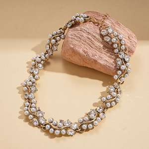 Macro shot of vintage baroque pearl necklace with rhinestones on a textured stone