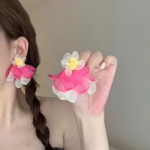 Detail of pink and cream organza flower earrings worn by a model in soft natural light