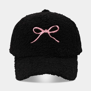 Close-up of black fleece baseball cap with pink bow embroidery and soft wool texture