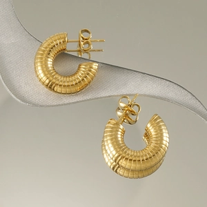 Boucles d'oreilles spirales en or 18 carats pour femme sur une surface réfléchissante