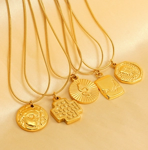 Detail of five gold coin necklaces with Medusa, snake and queen pendants on silk fabric