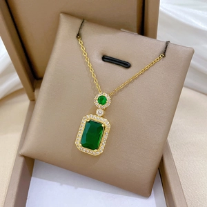 Macro detail of gold necklace with rectangle emerald pendant in premium jewelry box